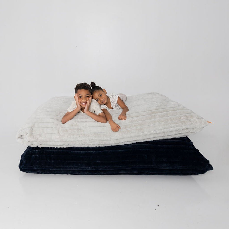 Two kids lying on stacked Baggies