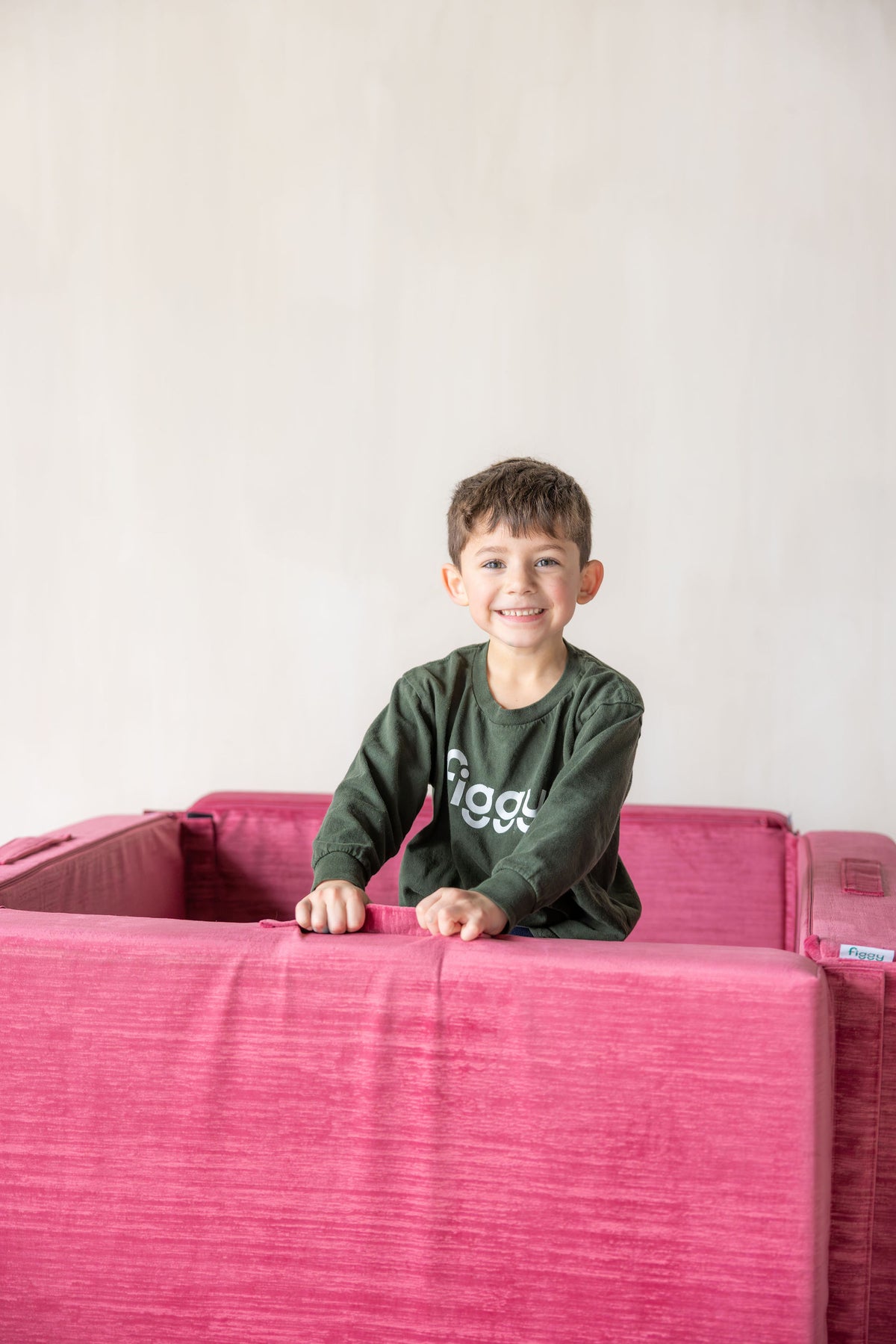 Boy playing inside a pink Figgy play couch built into a rectangle foam pit