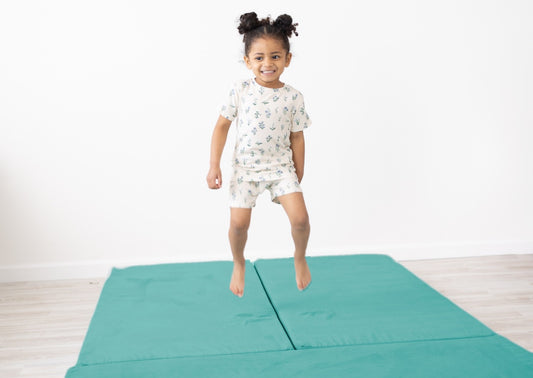 Girl jumping on Figgy Adventure Mats in Glacier Pool luxe velvet