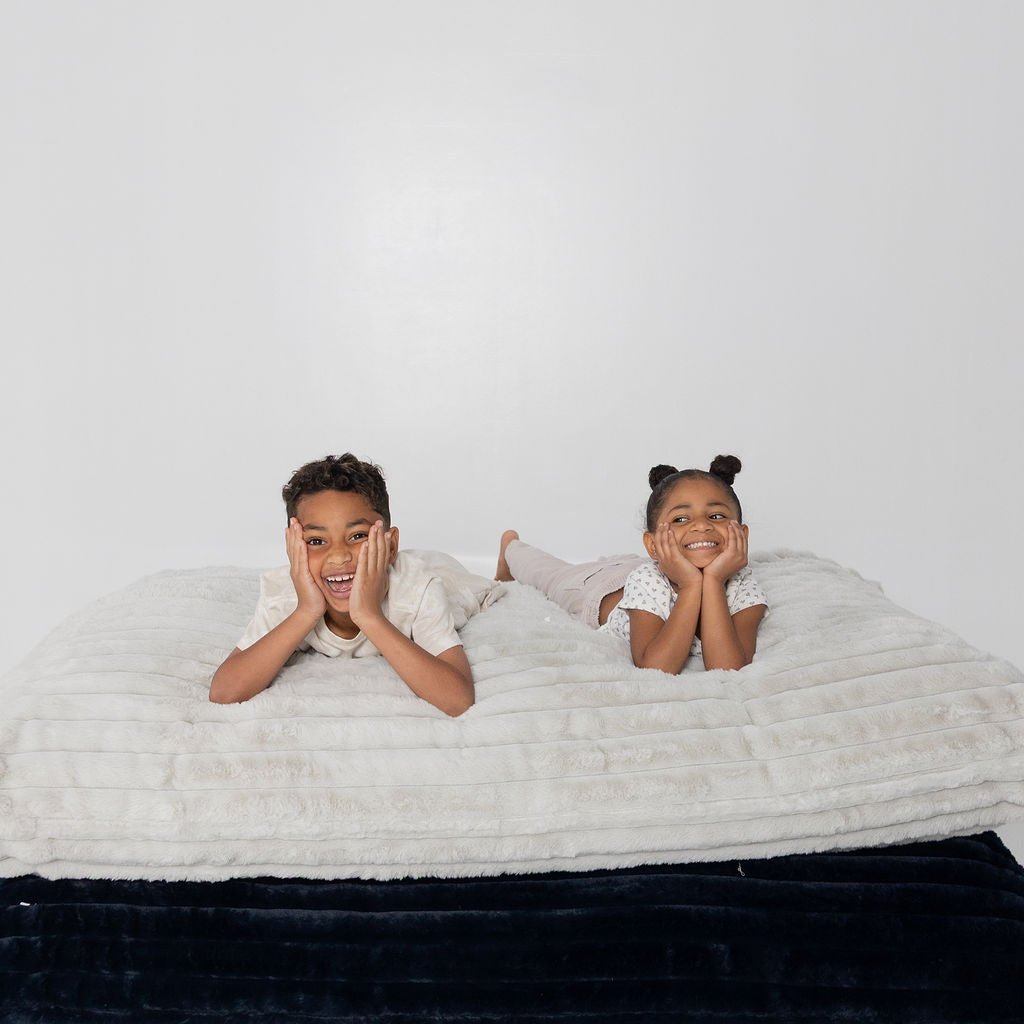 Two kids grinning, chins on hands, on stacked Baggies